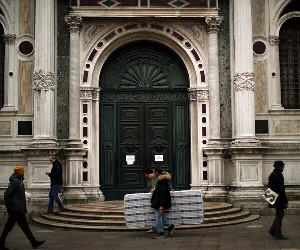 people walk past a closed church in venice, italy. 