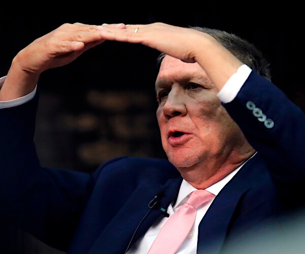 former ohio republican governor john kasich makes a large oval with his arms and hands over his head while speaking