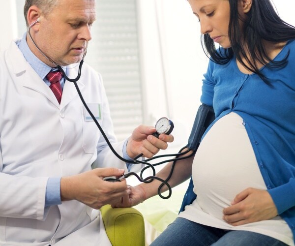 doctor taking blood pressure of pregnant woman
