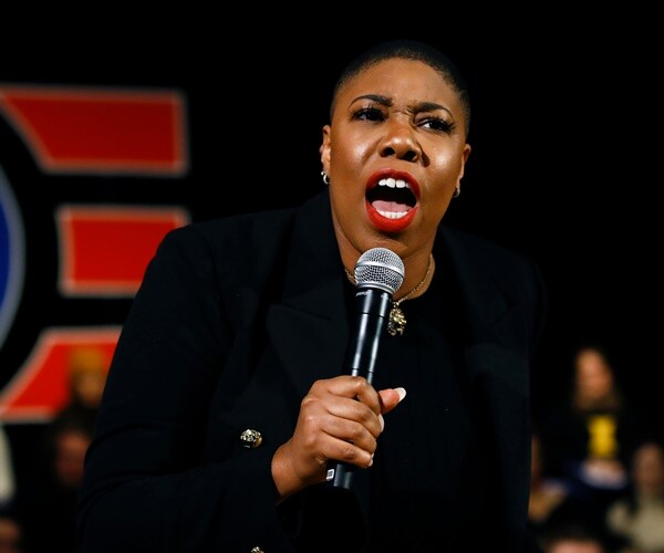symone sanders holds a mic and speaks at a biden event