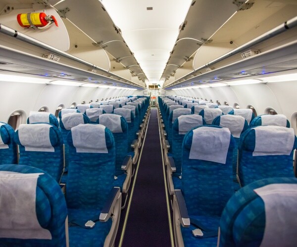 inside of an airplane with blue seats and open overhead storage 