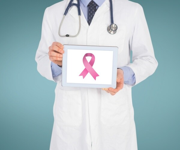 breast cancer ribbon is shown on an ipad screen held up by a doctor in a lab coat