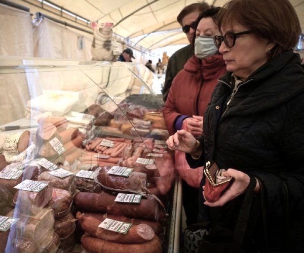 shoppers look over meat products at a market in moscow
