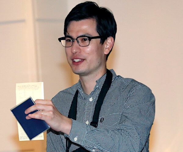 alek sigley holds up his australian passport and documents when he arrives in japan after his release