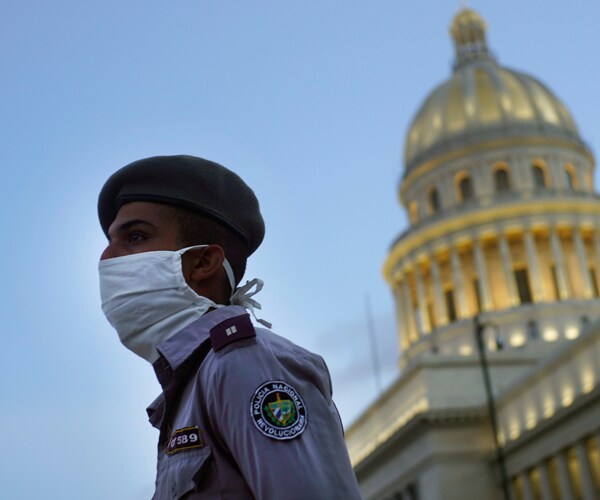 a police officer stands near the cuban capitol in havana