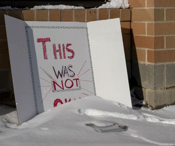 sign posted outside high school saying "this is not OK"