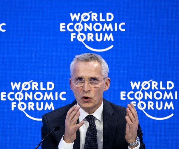 a man speaks with logos for the world economic forum around him