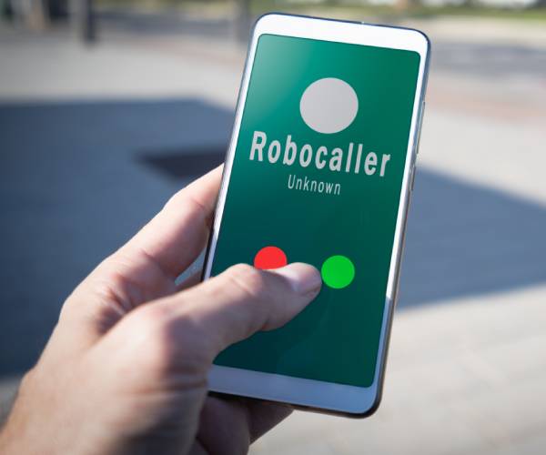 a hand holds a cellphone with the words robocaller unknown on it