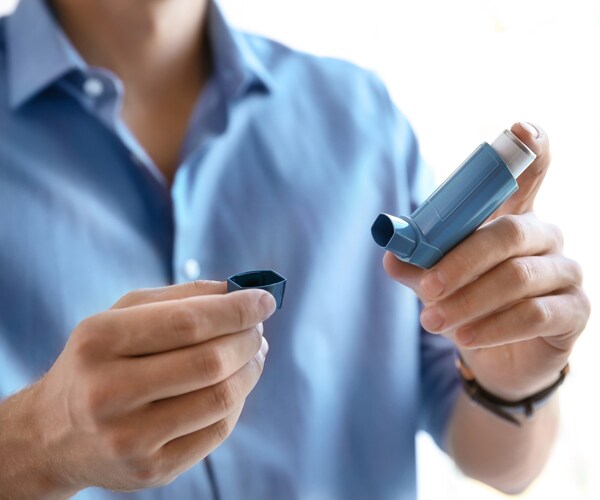a man holding an asthma inhaler