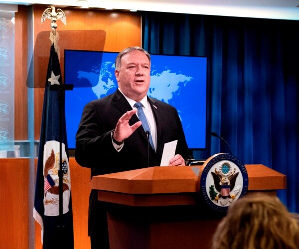 mike pompeo stands at a podium in the state department briefing room and speaks