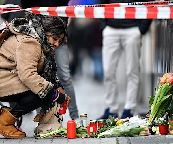 A woman sets a candle near the hookah bar scene where several people were killed late Wednesday in Hanau
