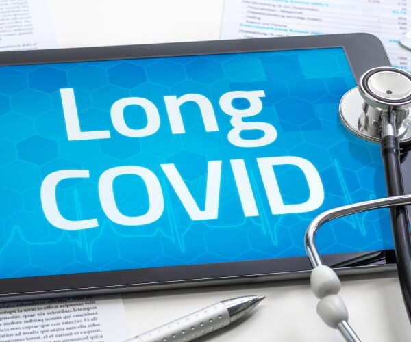 tablet that says Long COVID on the screen, stethoscope, pills