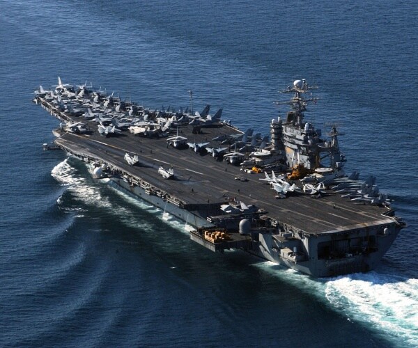 aircraft carrier in the ocean with many jets parked on top of it