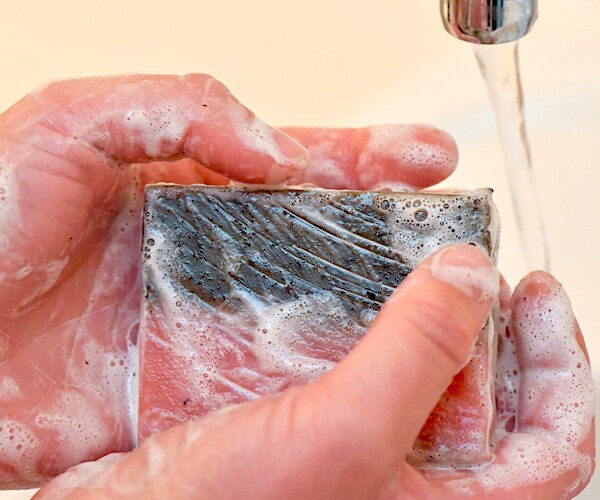 soapy hands are being washing under a faucet