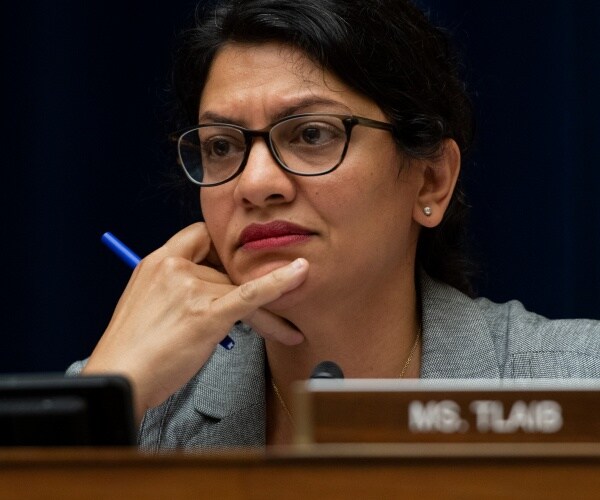 Rashida Tlaib holding a pen while sitting at a table 