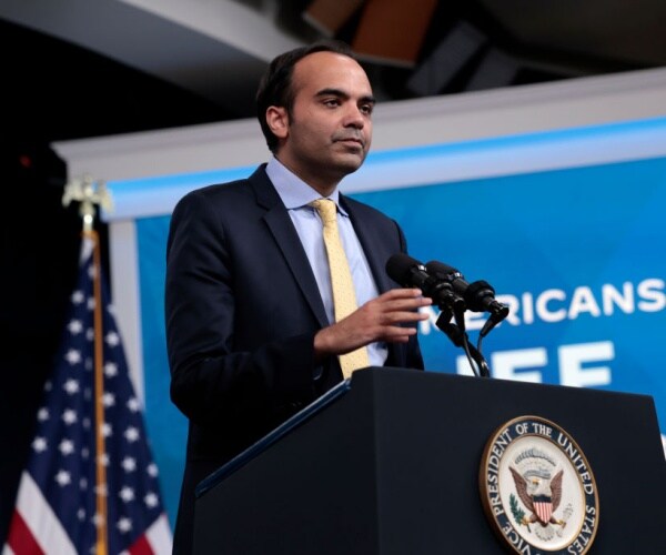 rohit chopra behind microphones and podium with presidential seal