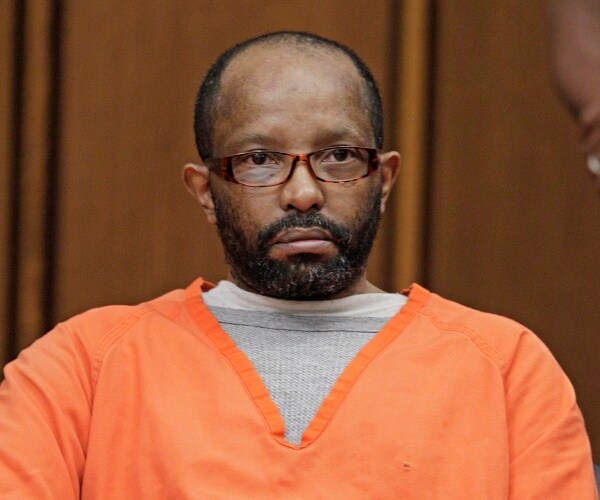 sowell in an orange prison uniform sitting down