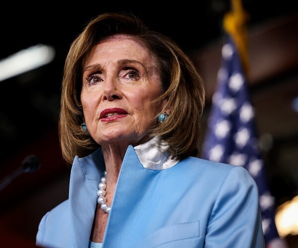 nancy pelosi stands behind podium
