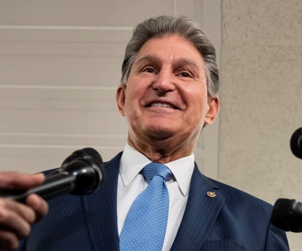 joe manchin smiles and speaks to reporters