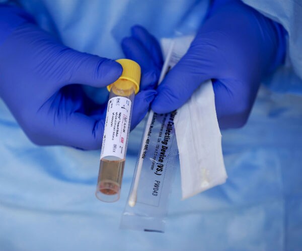 a health care worker shown components of a coronavirus test kit