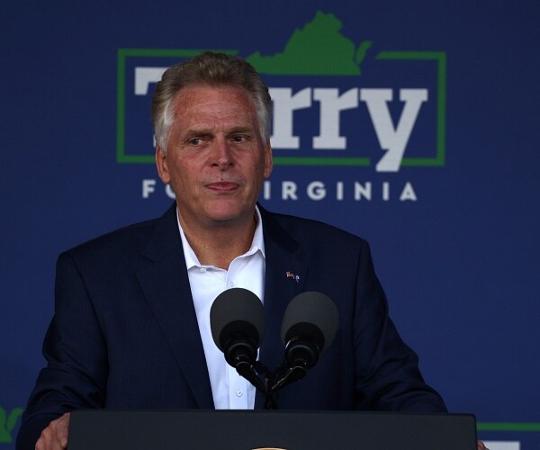 terry mcauliffe stands behind podium