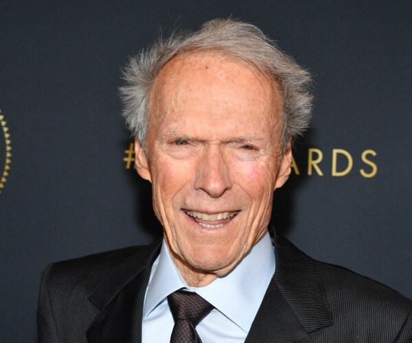 eastwood in a black suit light blue shirt and black tie