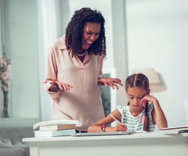 mother yelling at young girl doing homework