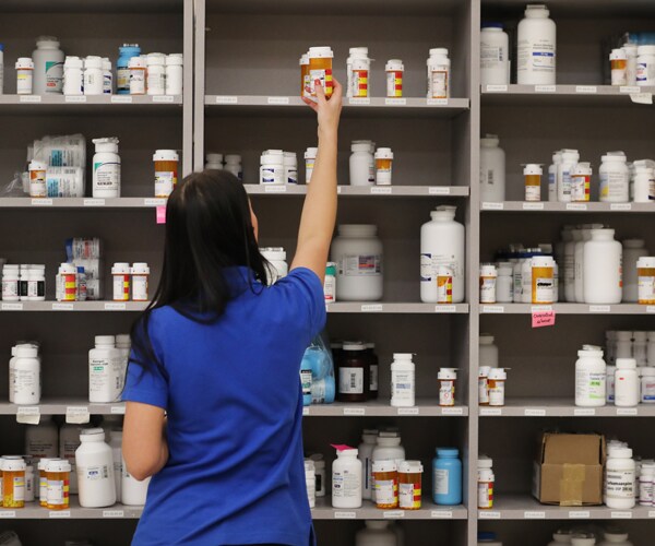 a pharmacist grabs medicine off a shelf