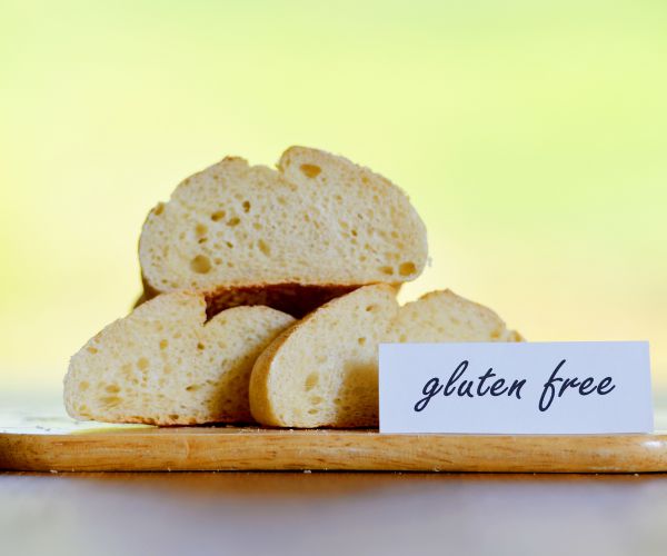 sliced gluten free bread on a cutting board with a gluten free sign