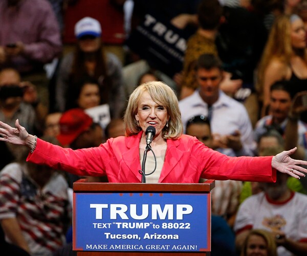jan brewer extends both arms out during a campaign rally