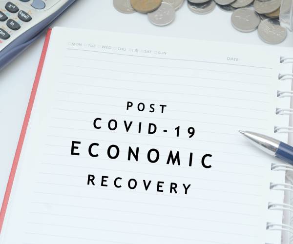 coins in a jar with a calculator and post covid 19 economic recovery written on a planner