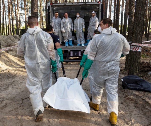 rescue workers carry bodies from unidentified graves izium, ukraine