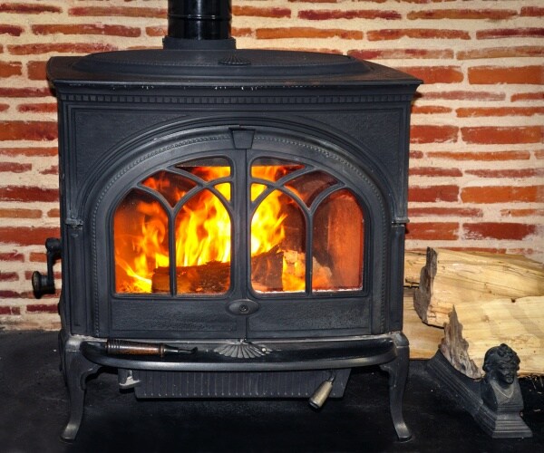 wood burning stove is shown with firewood beside it