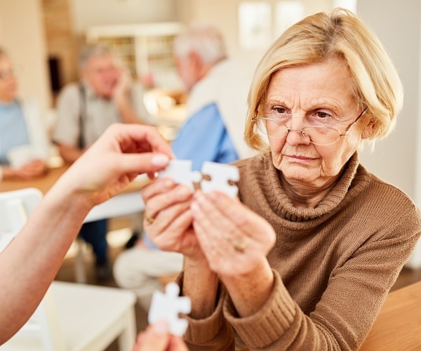 older woman putting together two puzzle pieces