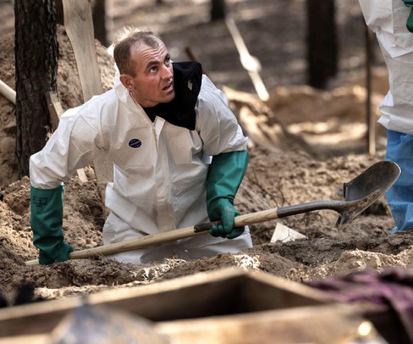 rescue workers exhuming bodies from makeshift graves in izium, ukraine