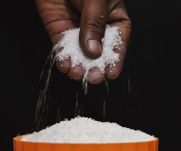 an indian man, only hand seen, keeps sugar in a pot.
