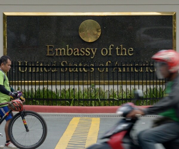 us embassy in the philippines with people biking and walking in front