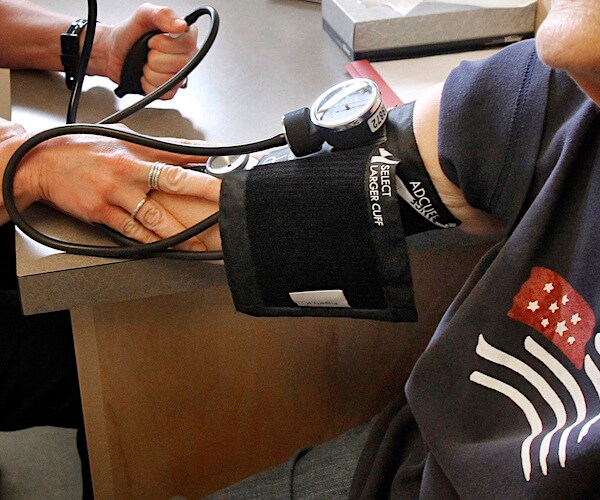 a person gets a blood pressure test from a nurse in a chair at a table