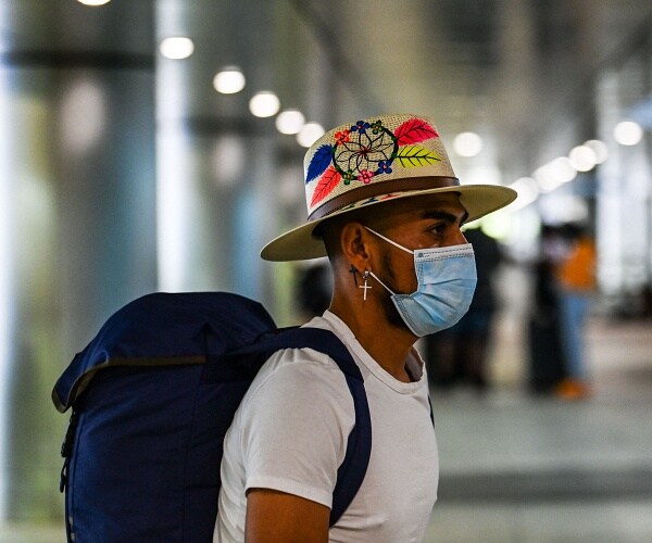man wearing mask walks into airport