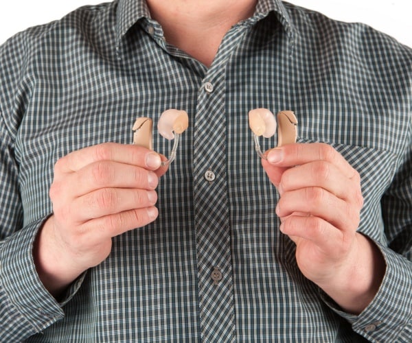 man holding a hearing aid in each hand