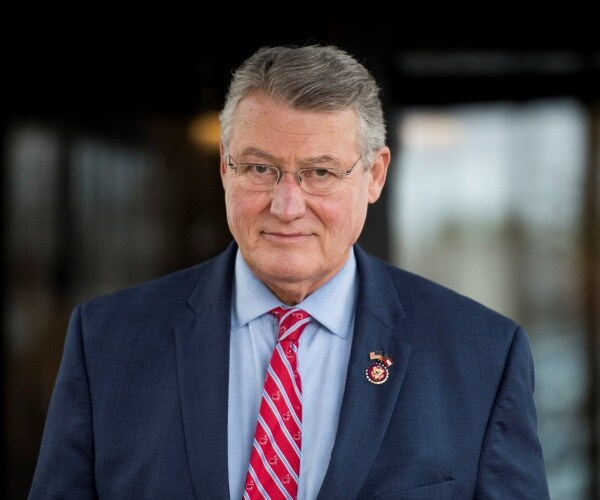 allen in a navy blue suit and red striped tie