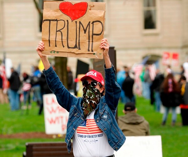 a protester of stay-at-home orders holds and I love trump sign