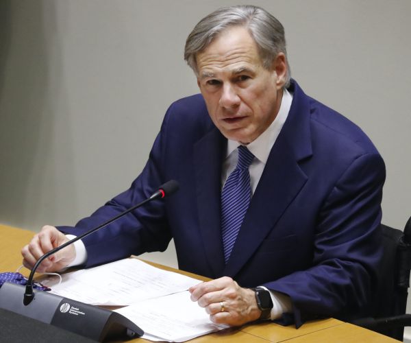 greg abbott sits and speaks at a news conference