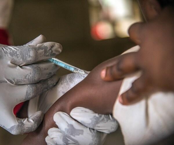 a baby's are is held while they get a measles vaccination