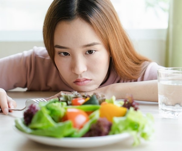 girl looking bored as she looks at a salad