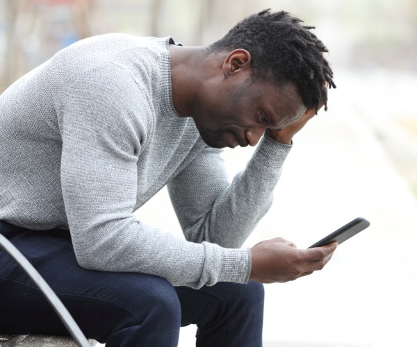 man depressed looking at news on phone