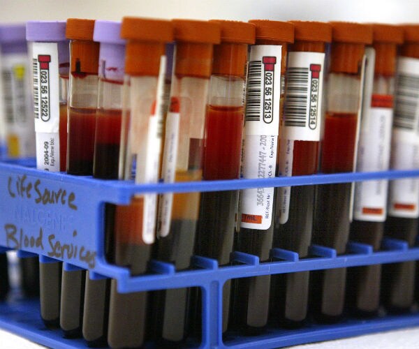 Tubes of testing-in-process donated blood are visible shown in a testing lab