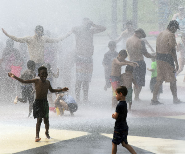 Children and adults escape 90 degree temperatures as they cool off in The Whirlpool Compass Fountain in Michigan