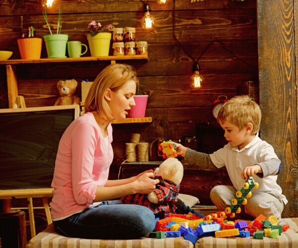 woman in pink shirt playing with a little boy 