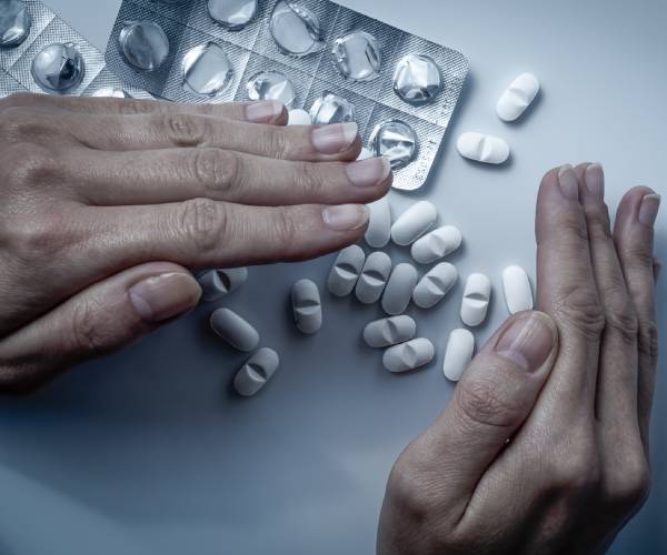 hands trying to hide a pile of pills